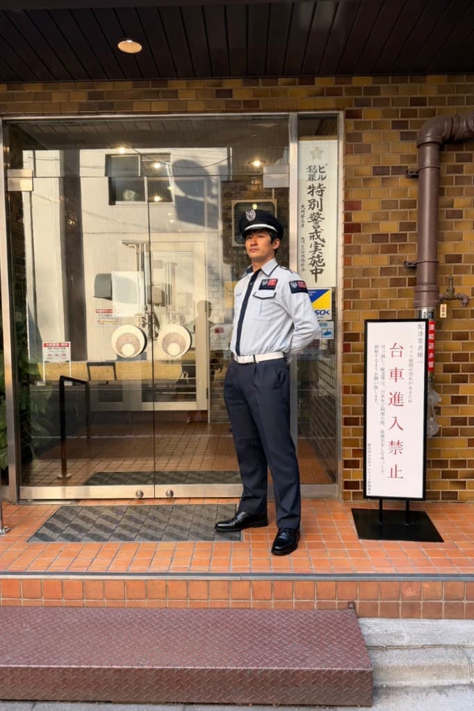 ビル入口で立哨する男性施設警備員